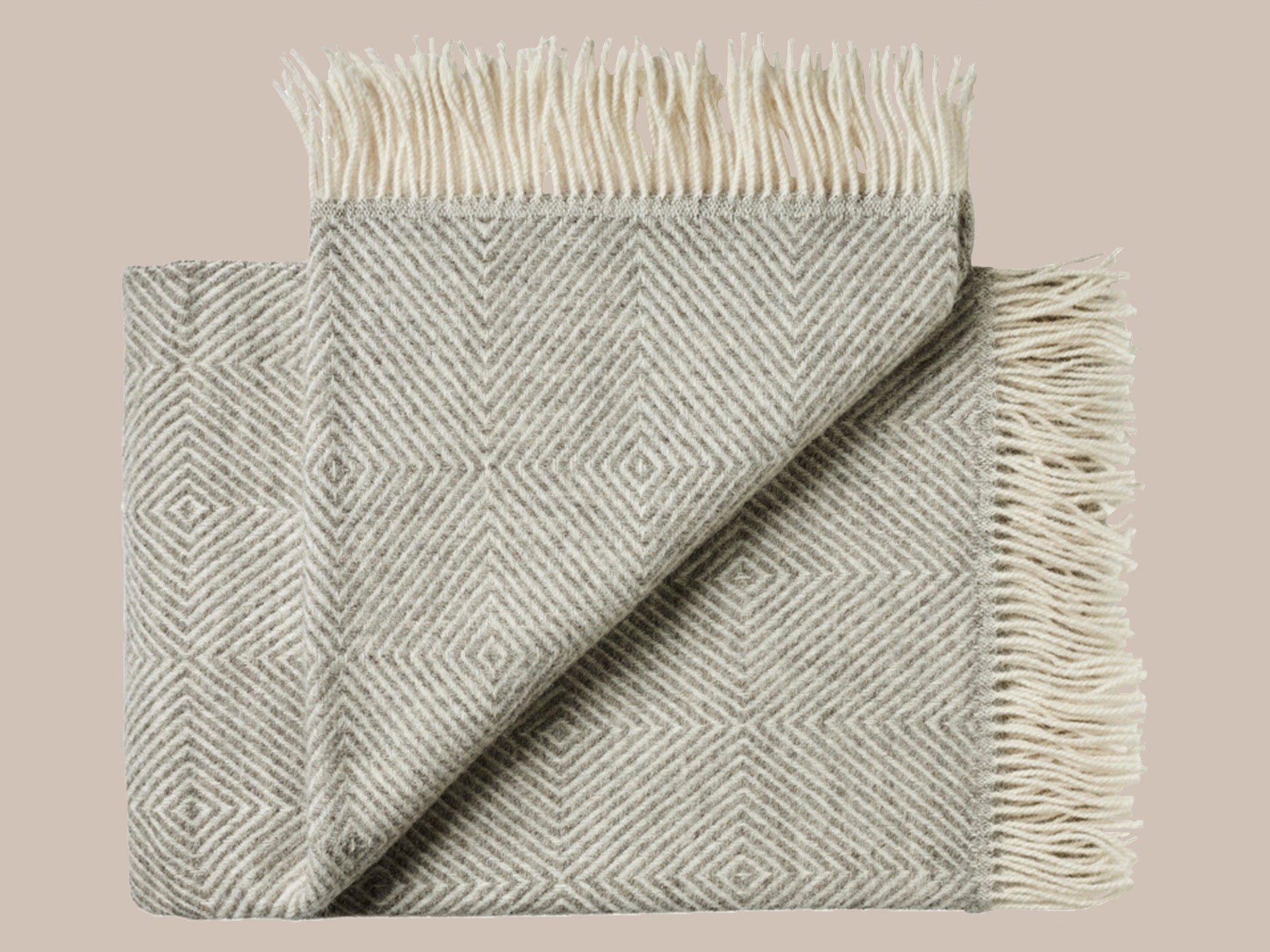 Uldplaid med frynser i skandinavisk uld i de smukkeste naturlige farver og mønstre. Et varmt bæredygtigt uldtæppe til dig , der elsker at varme dig med et tæppe.. Dette tæppe er i et smukt afstemt mønster i lys beige og lys grå med lys beige frynser.