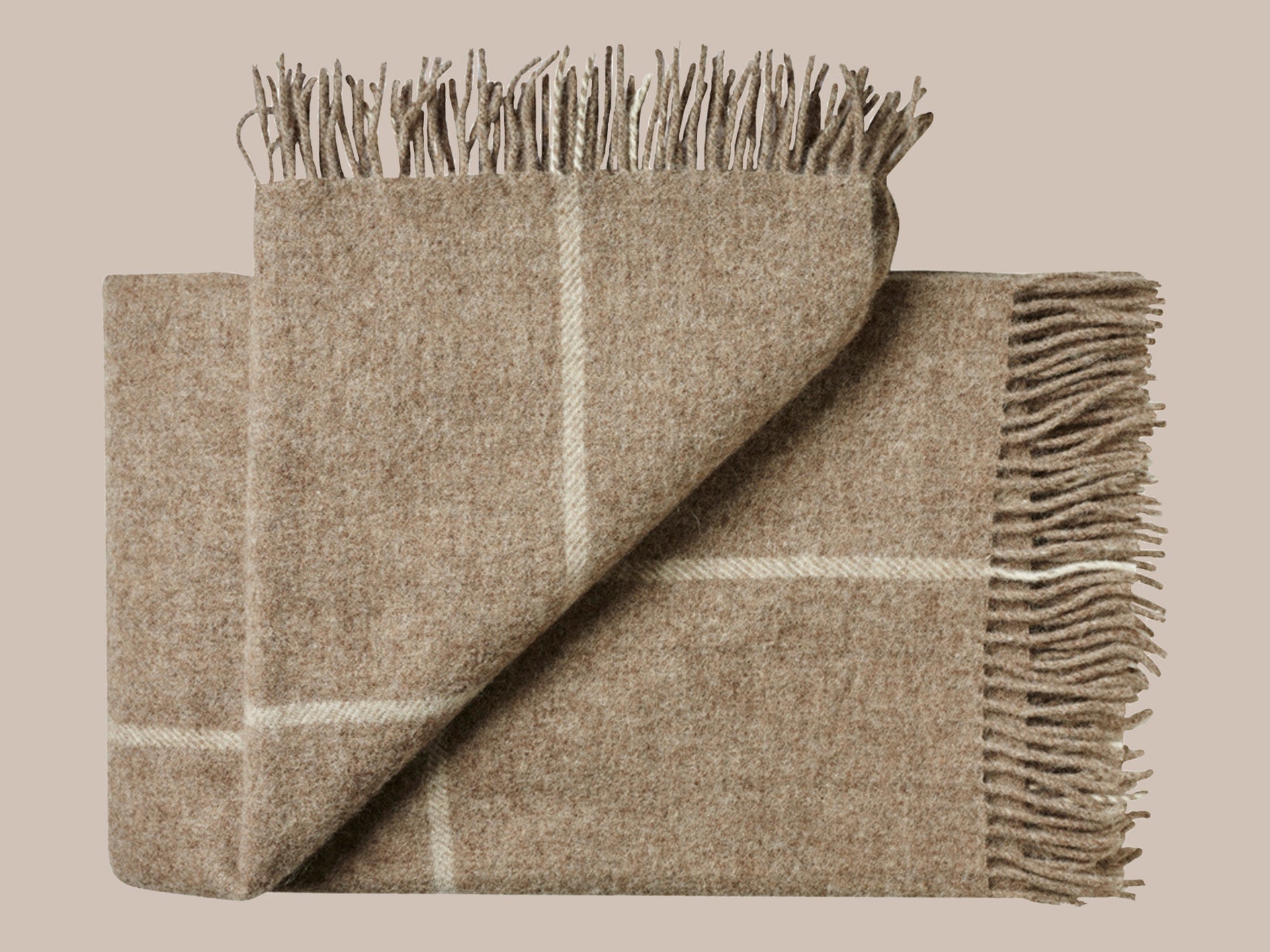 Uldplaid med frynser i skandinavisk uld i de smukkeste naturlige farver og mønstre. Et varmt bæredygtigt uldtæppe til dig , der elsker at varme dig med et tæppe.. Dette tæppe er et chokoladefarvet storternet tæppe med lys beige. Et smukt afstemt mønster